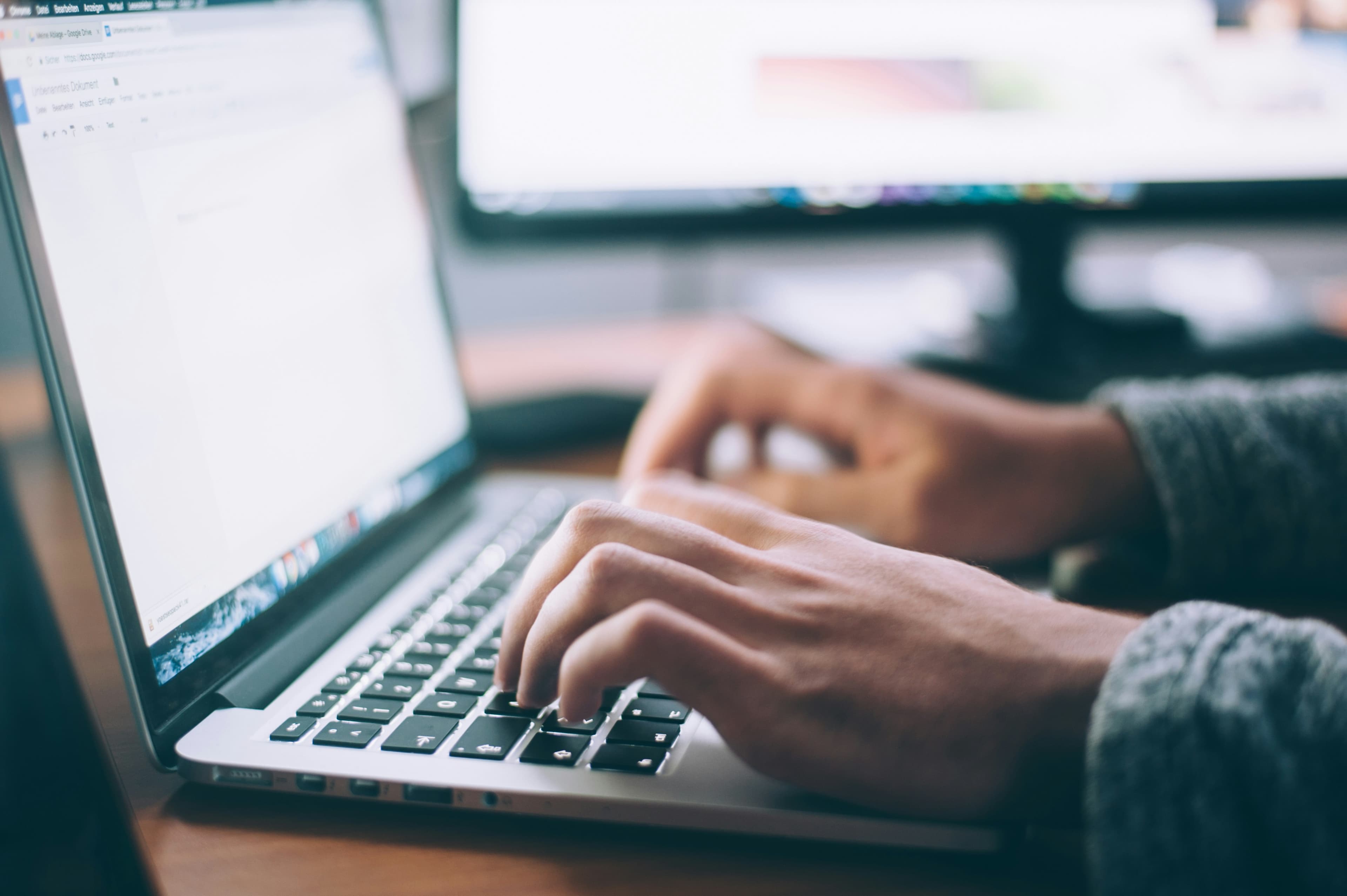 Person typing on a laptop while working on written feedback